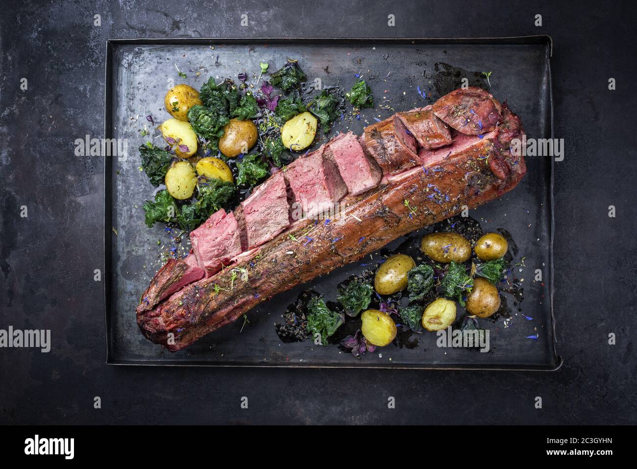 Barbecue filetto di cervo stagionato secco bistecca e sella naturale con kalette e patate fritte offerto come vista dall'alto su un RU Foto Stock