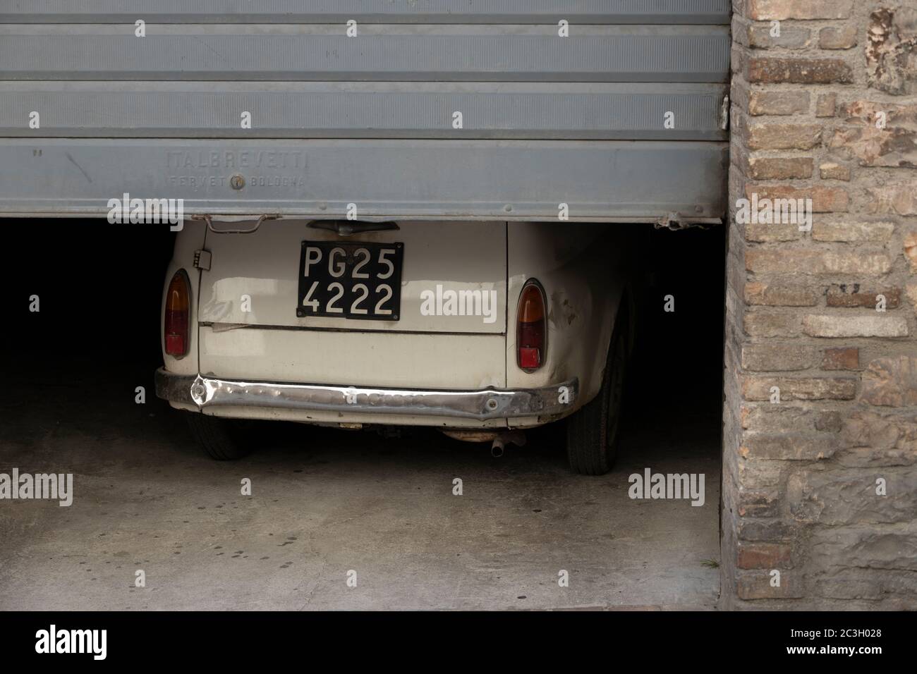 Un'antica utilitaria italiana esce da un garage in un borgo italiano Foto Stock