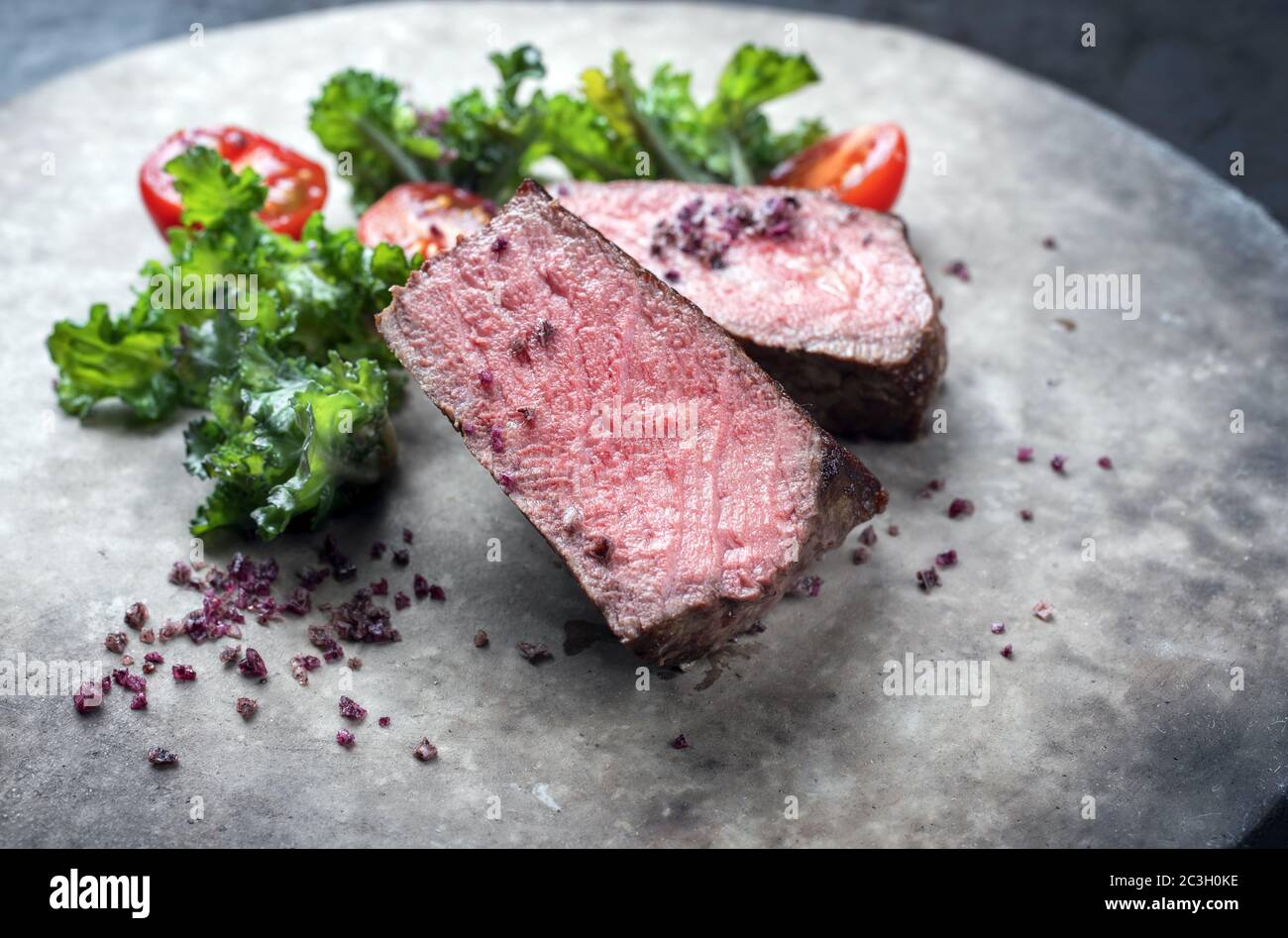 Barbecue arrosto di manzo di wagyu stagionato naturale affettato con rapini e tomatos come closeup su una piastra di design moderno Foto Stock