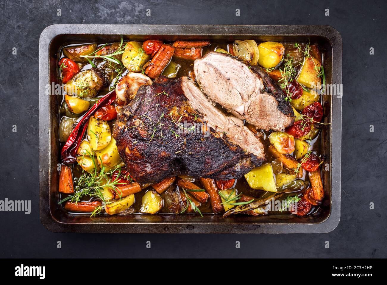 Tradizionale arrosto di agnello barbecue affettato con pomodori e patate fritte come vista dall'alto in un vassoio di metallo Foto Stock