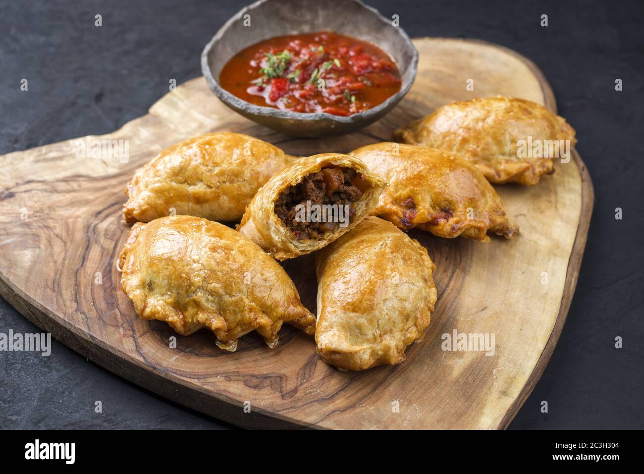Tradizionale empanada de carne sudamericana offerto con un tuffo chili come closeup su una rustica tavola di legno Foto Stock