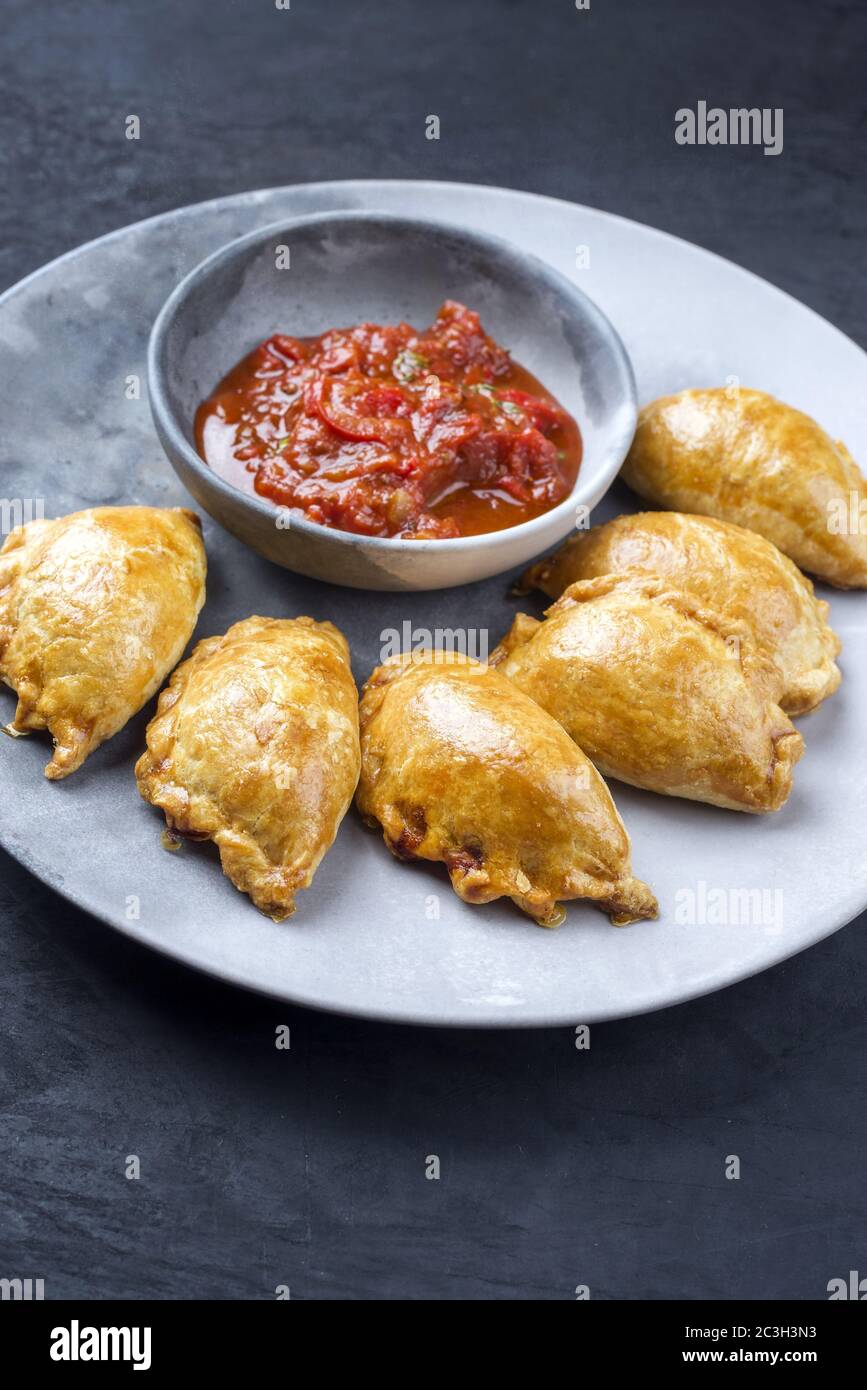 Tradizionale empanada de carne sudamericana offerto con un tuffo chili come primo piano su una piastra di design moderno Foto Stock