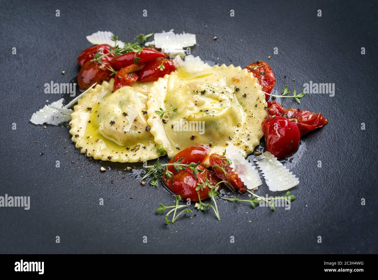 Tradizionale pasta di ravioli italiana con parmigiano e pomodori fritti come primo piano su un piatto dal design moderno Foto Stock