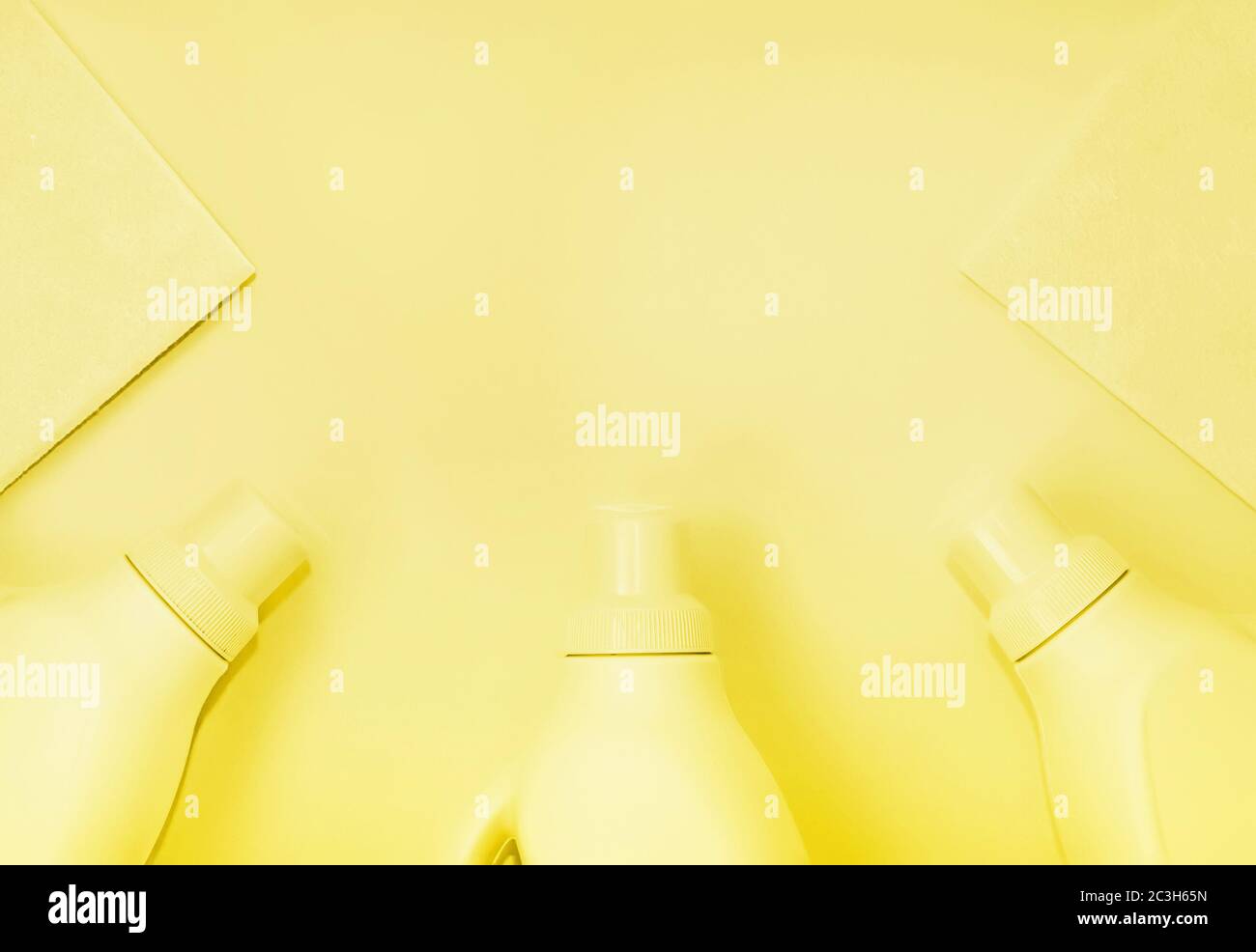 Bottiglie in plastica con prodotti chimici per la pulizia, stracci per la pulizia. Colorazione gialla, sfondo giallo. Concetto di pulizia Foto Stock