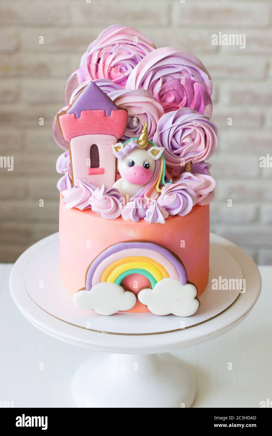 Carino torta rosa di compleanno per una bambina con fondente unicorno, il  castello della principessa di pan di zenzero, arcobaleno e meringa nuvole  Foto stock - Alamy