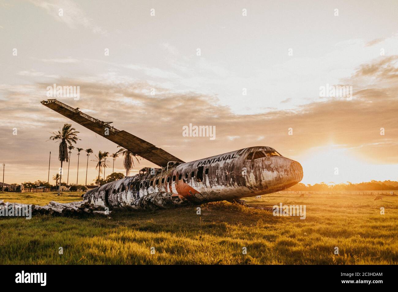 Aereo abbandonato su un campo di erba con un sole incandescente sullo sfondo Foto Stock