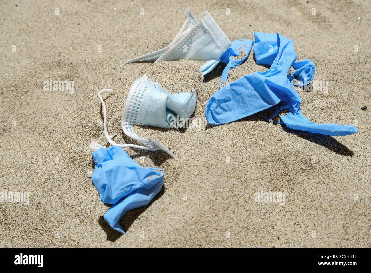 Maschera virus e guanti di plastica spazzatura sulla costa del mare, malattia di inquinamento da covidi coronavirus, ecosistema sporco Foto Stock