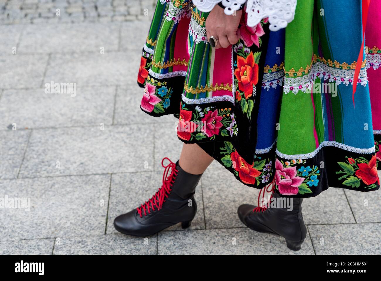 Donna vestita in un elegante costume popolare nazionale della regione di Lowicz. Primo piano di tradizionali abiti tradizionali a righe, scarpe e ricami a strisce Foto Stock