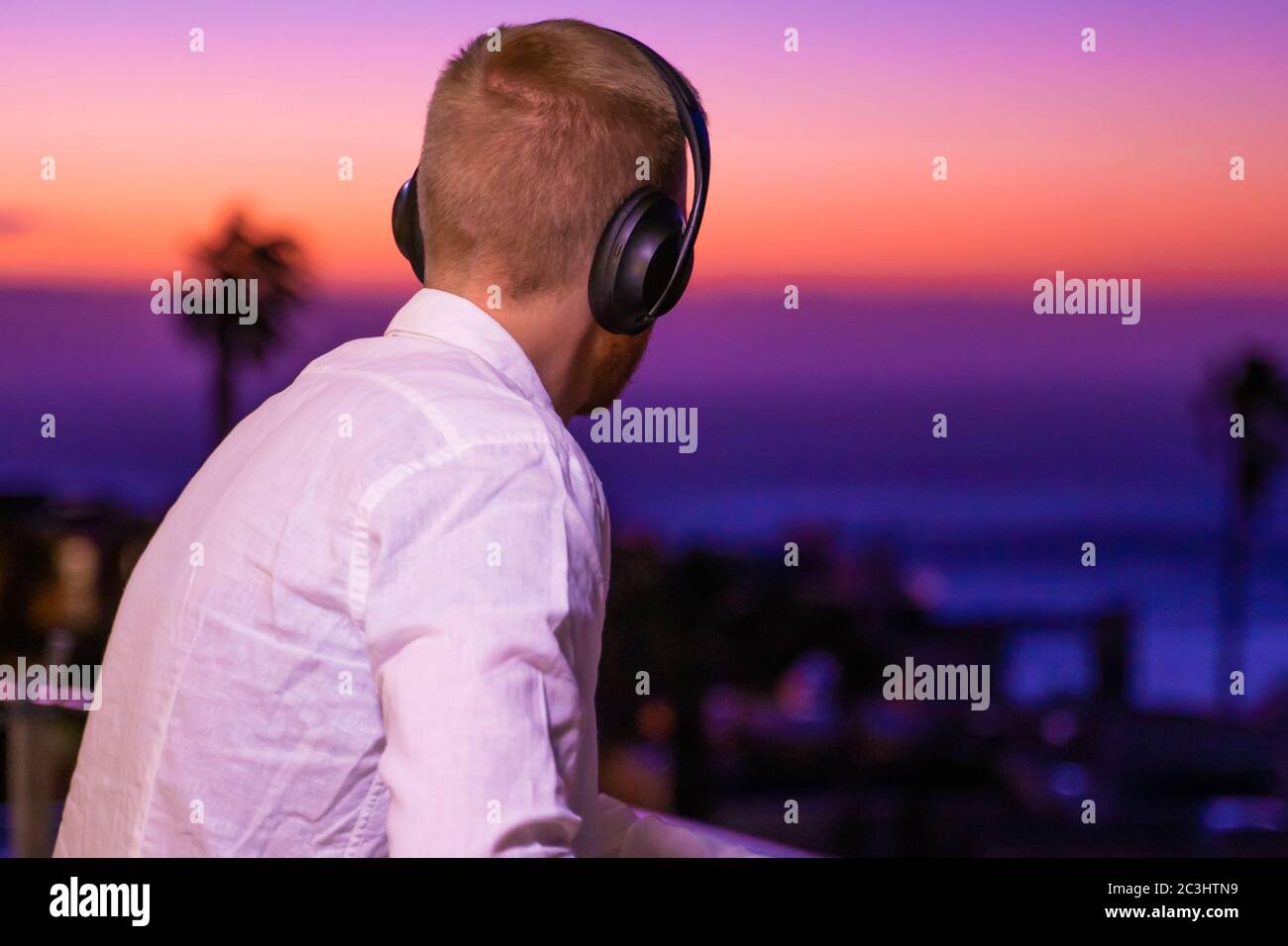 CAPETOWN, SUDAFRICA - 22 febbraio 2020: Un giovane che guarda un tramonto colorato mentre ascolta la musica a Capetown, in Sud Africa Foto Stock