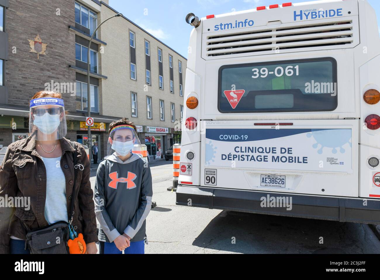 Madre & figlio che indossa maschere facciali e schermi facciali protettivi durante il Pandemic Covid-19 in piedi davanti alla clinica mobile di test Covid19, Montreal Foto Stock