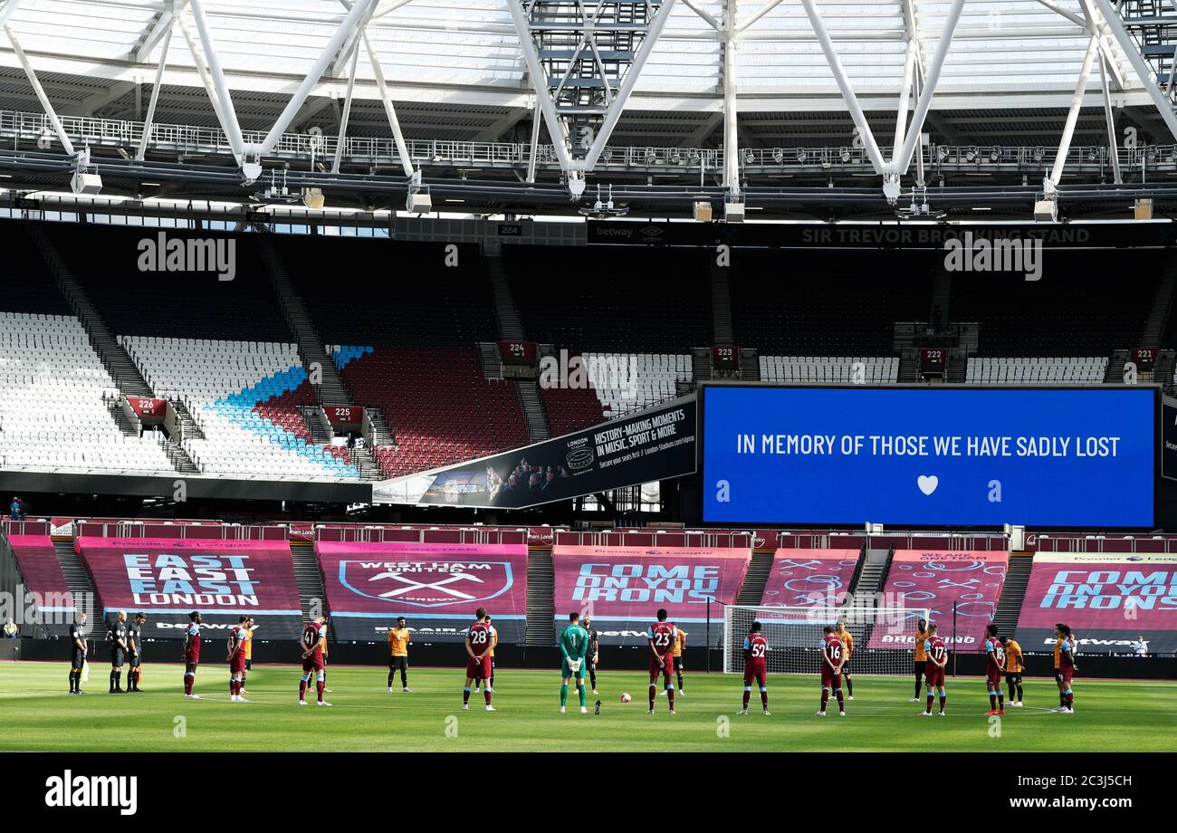 Giocatori e funzionari si levano in piedi per un minuto di silenzio in memoria delle vittime del coronavirus prima della partita della Premier League al London Stadium. Foto Stock