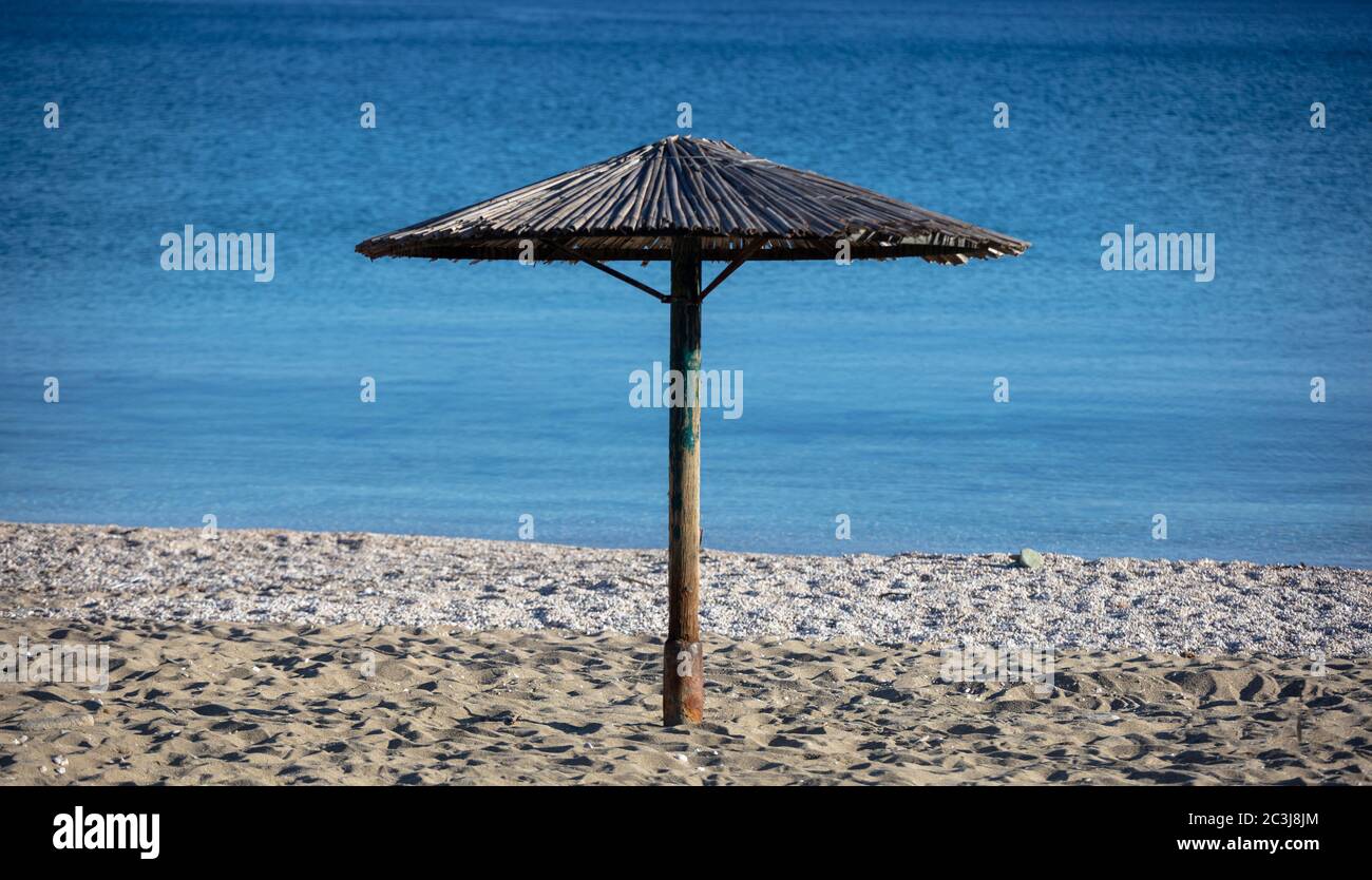 Ombrellone in paglia su una spiaggia di sabbia vuota. Blu calmo sfondo mare, soleggiata giornata di primavera Foto Stock