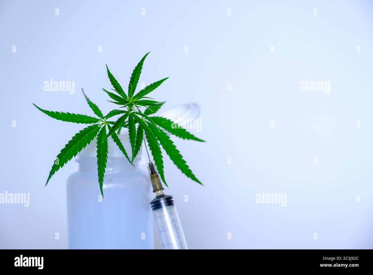 Foglia di marijuana, vaso di plastica con cannabis e siringa su sfondo bianco Foto Stock