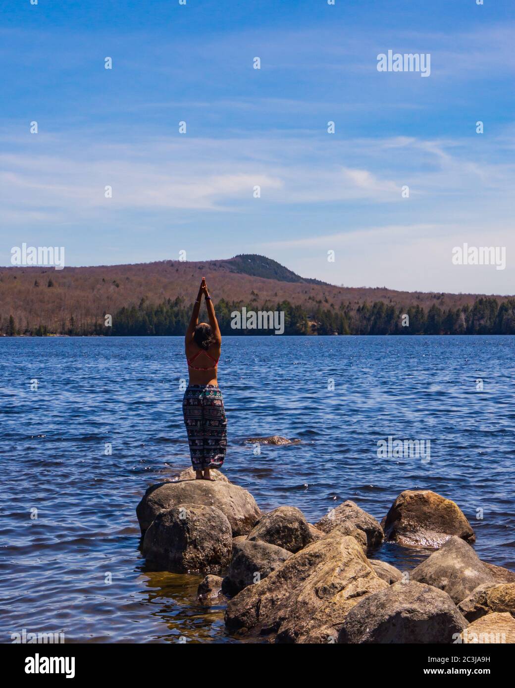 Donna che pratica 'un salutation' yoga posa su Peacham Pond in Vermont Foto Stock