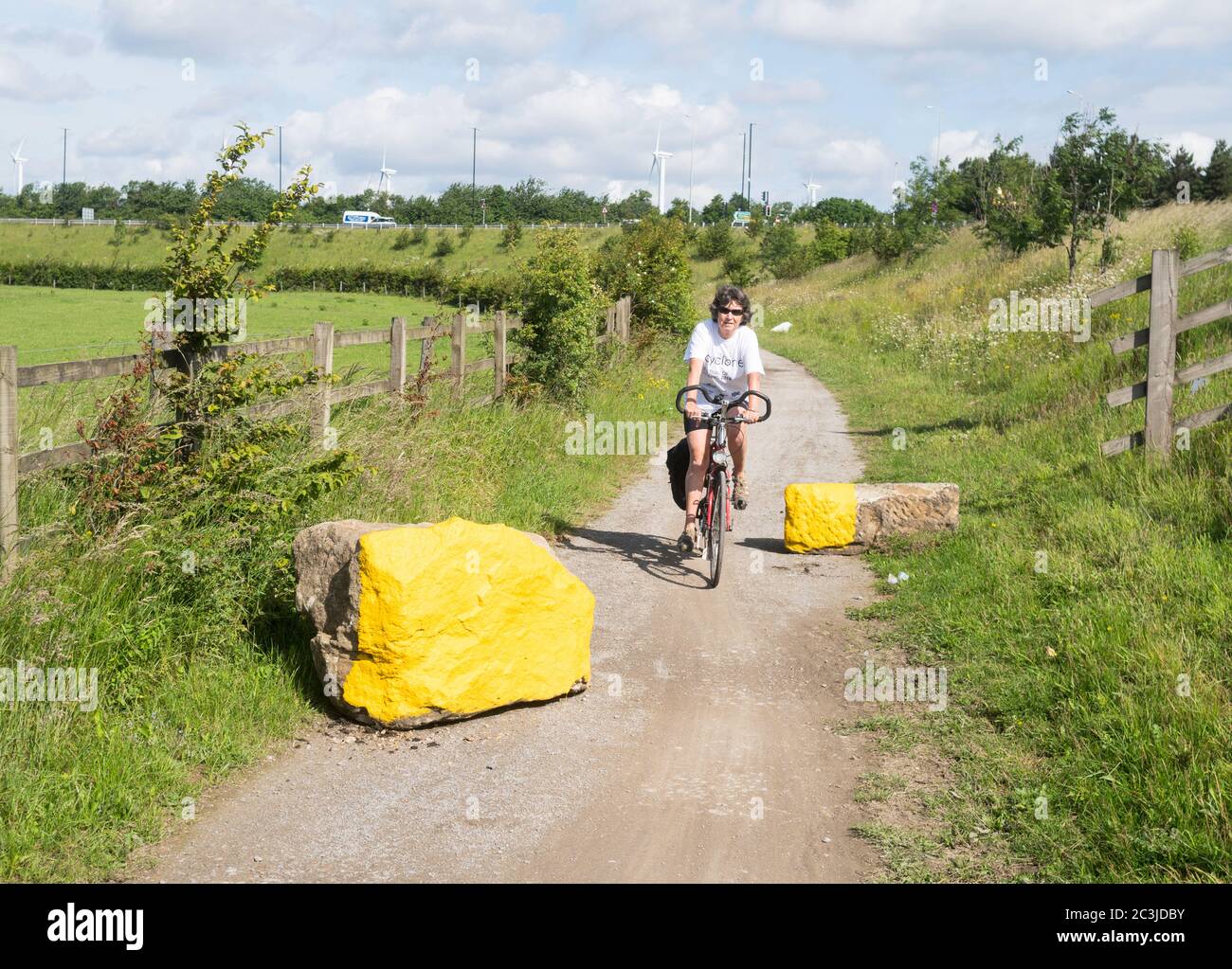 Una donna matura in bicicletta lungo la costa per costeggiare la pista ciclabile attraverso Sunderland, Inghilterra, Regno Unito Foto Stock