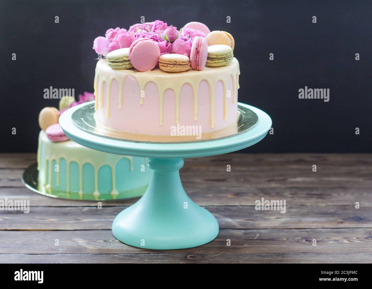 Elegante torta di nozze rosa decorata con cioccolato bianco fuso, belle rose  fresche e macaron francesi. Sfondo nero Foto stock - Alamy