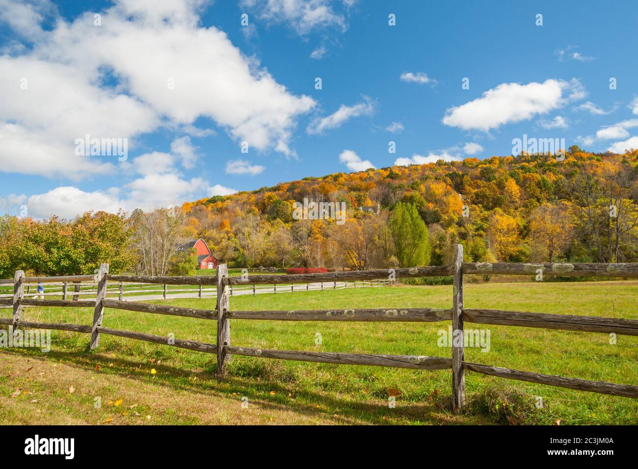 Dalla strada di campagna americana un paesaggio rurale con fienile rosso in distanza oltre posta rustica e recinzione ferroviaria nella contea di Kent, New England USA. Foto Stock