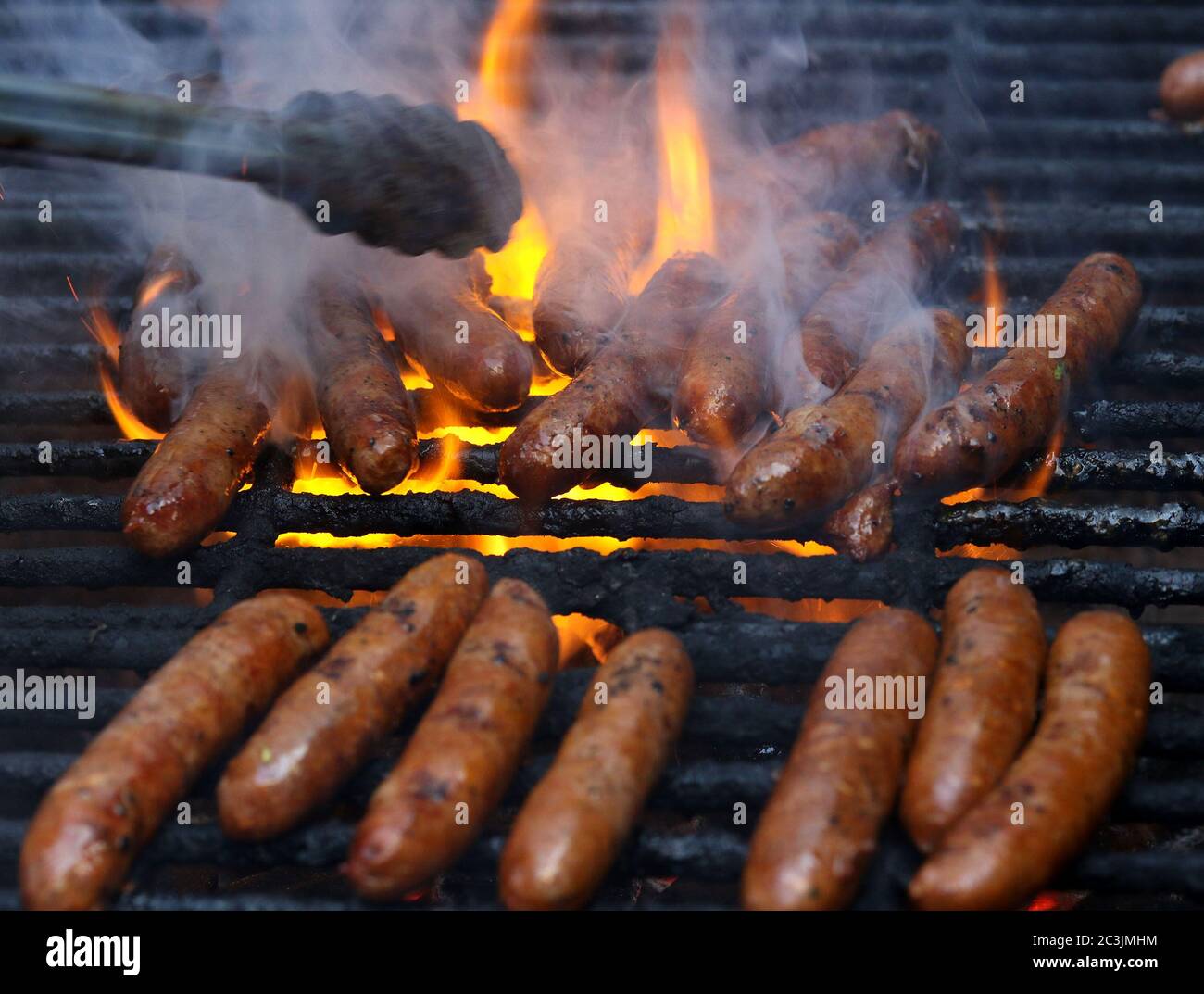 Salsicce cucinando su una griglia esterna Foto Stock