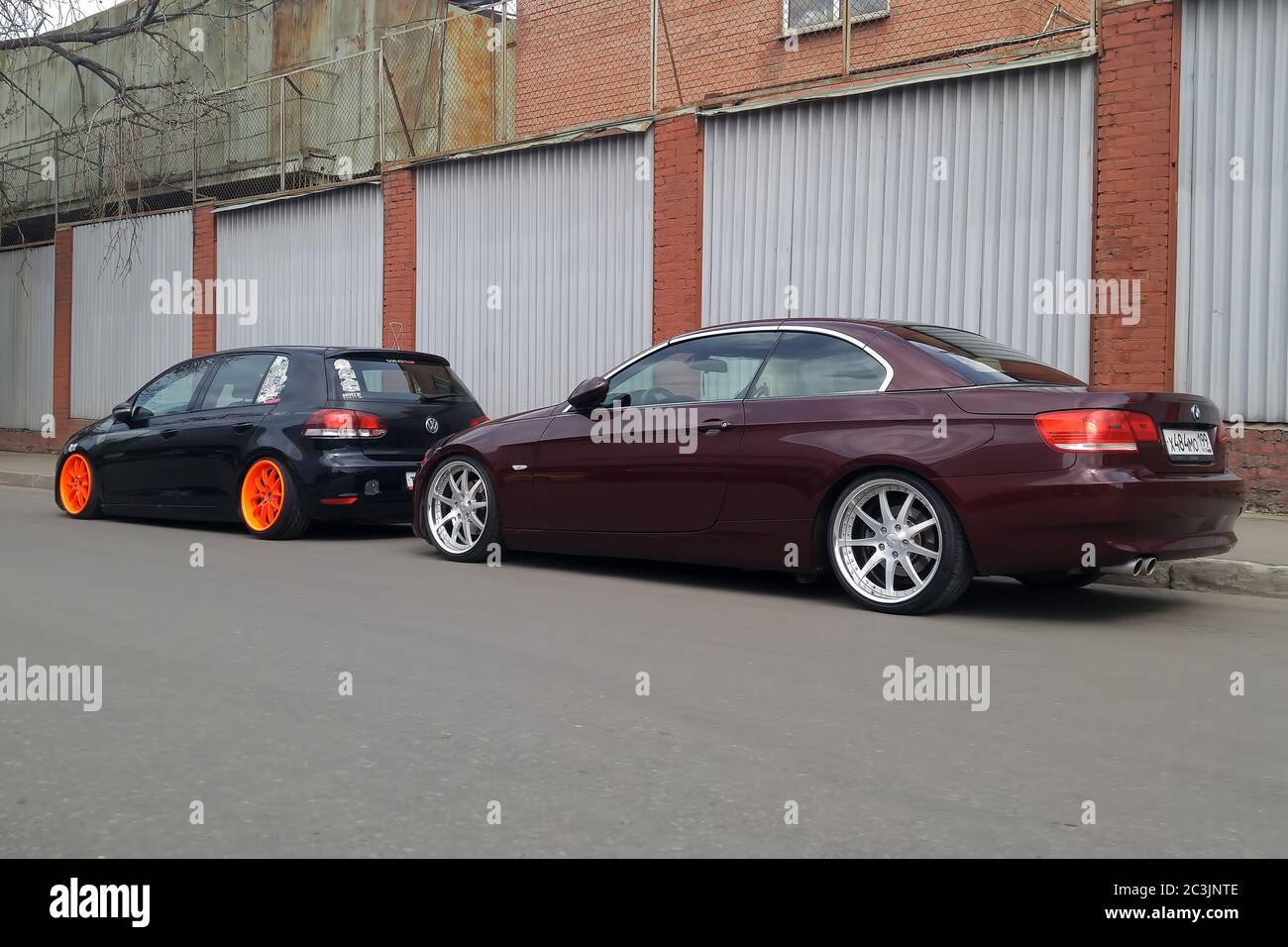 Mosca. Autunno 2018. Volkswagen golf nero con ampie ruote arancioni sintonizzate da sospensioni pneumatiche. E marrone BMW Serie 3 Cabriolet convertibile . Auto basse parcheggiate sulla strada. Foto Stock