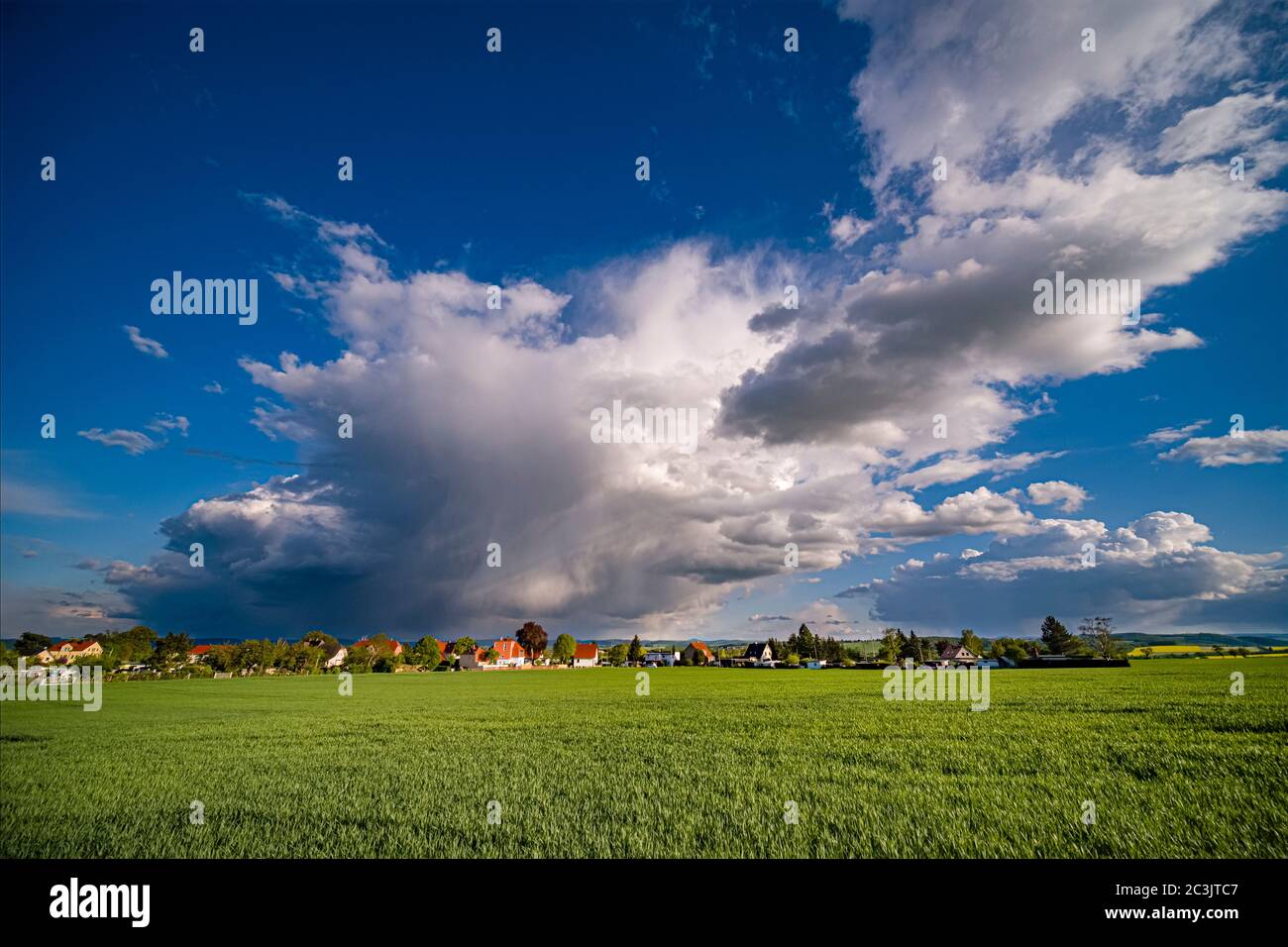 Paesaggio agricolo con un villaggio in lontananza, nubi oscure temporale in movimento Foto Stock