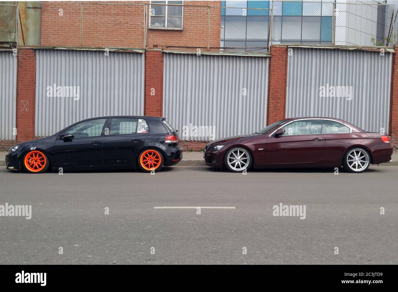 Mosca. Autunno 2018. Volkswagen golf nero con ampie ruote arancioni sintonizzate da sospensioni pneumatiche. E marrone BMW Serie 3 Cabriolet convertibile . Auto basse parcheggiate sulla strada. Foto Stock