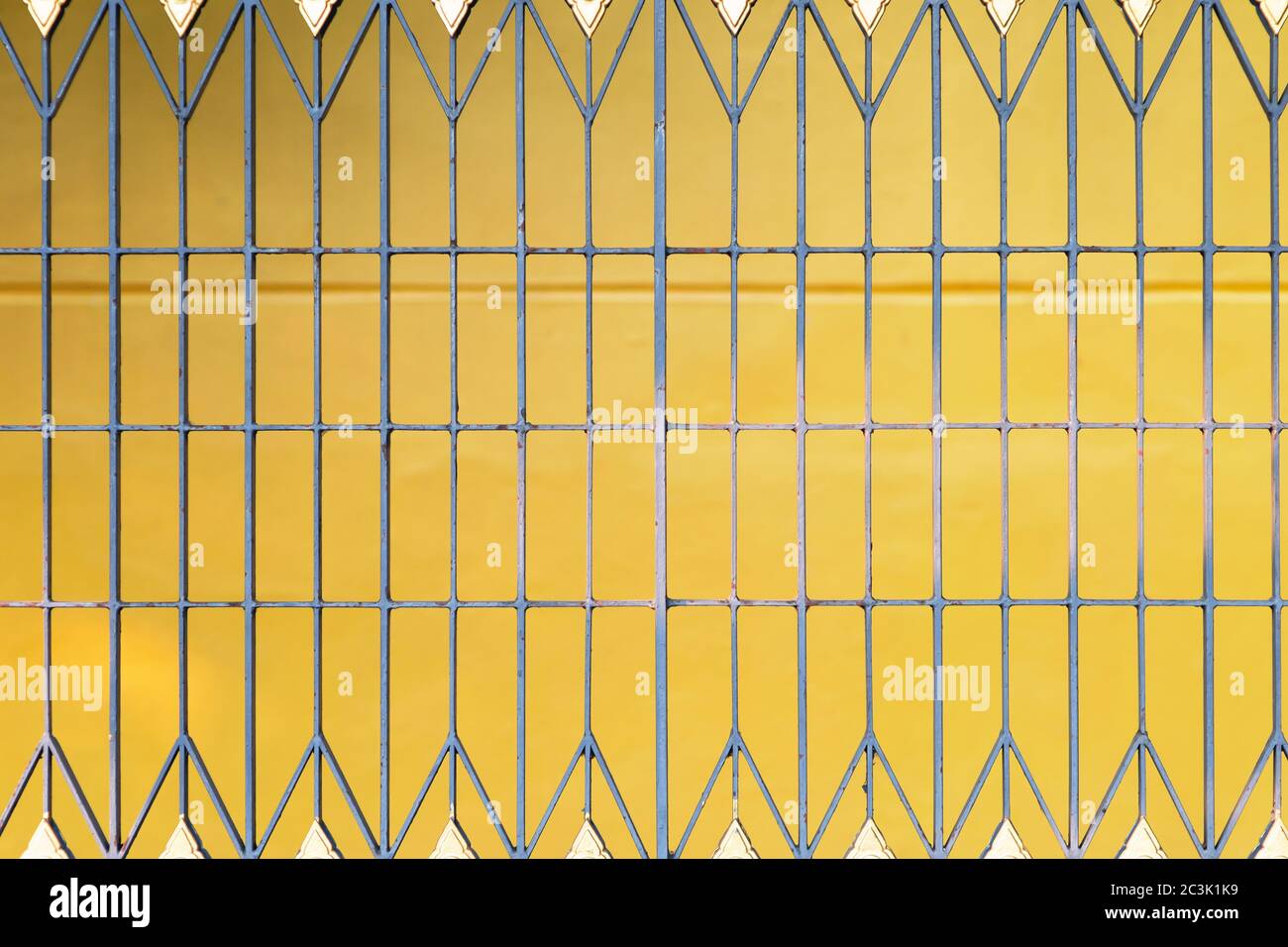 Chiudi su recinto di ferro con uno sfondo giallo.There è ruggine che cresce fuori dell'edificio. Foto Stock