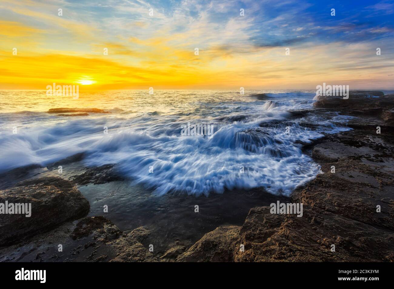 Onda in arrivo sulle rocce di arenaria della spiaggia di Turimetta intorno al promontorio di Narrabeen all'alba della costa del pacifico a Sydney. Foto Stock