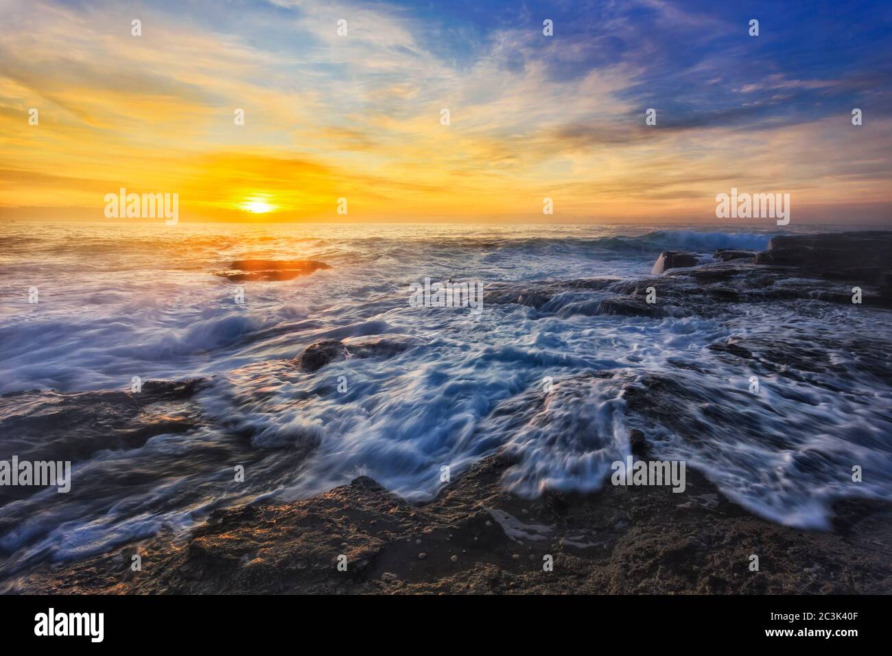 Forti onde dell'oceano Pacifico che si ondeggia su rocce di arenaria nella spiaggia di Turimetta sulle spiagge settentrionali di Sydney all'alba. Foto Stock