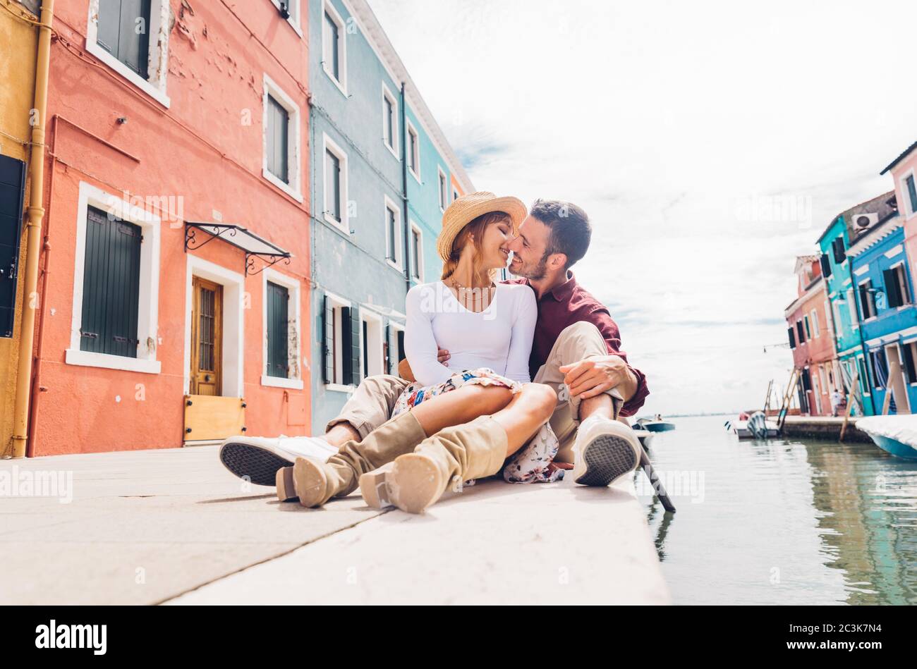 Romantico ragazzo e ragazza in amore baciando seduto sul canale di Venezia, Italia. Un turista adorabile che si gode una vacanza estiva in città. Foto Stock