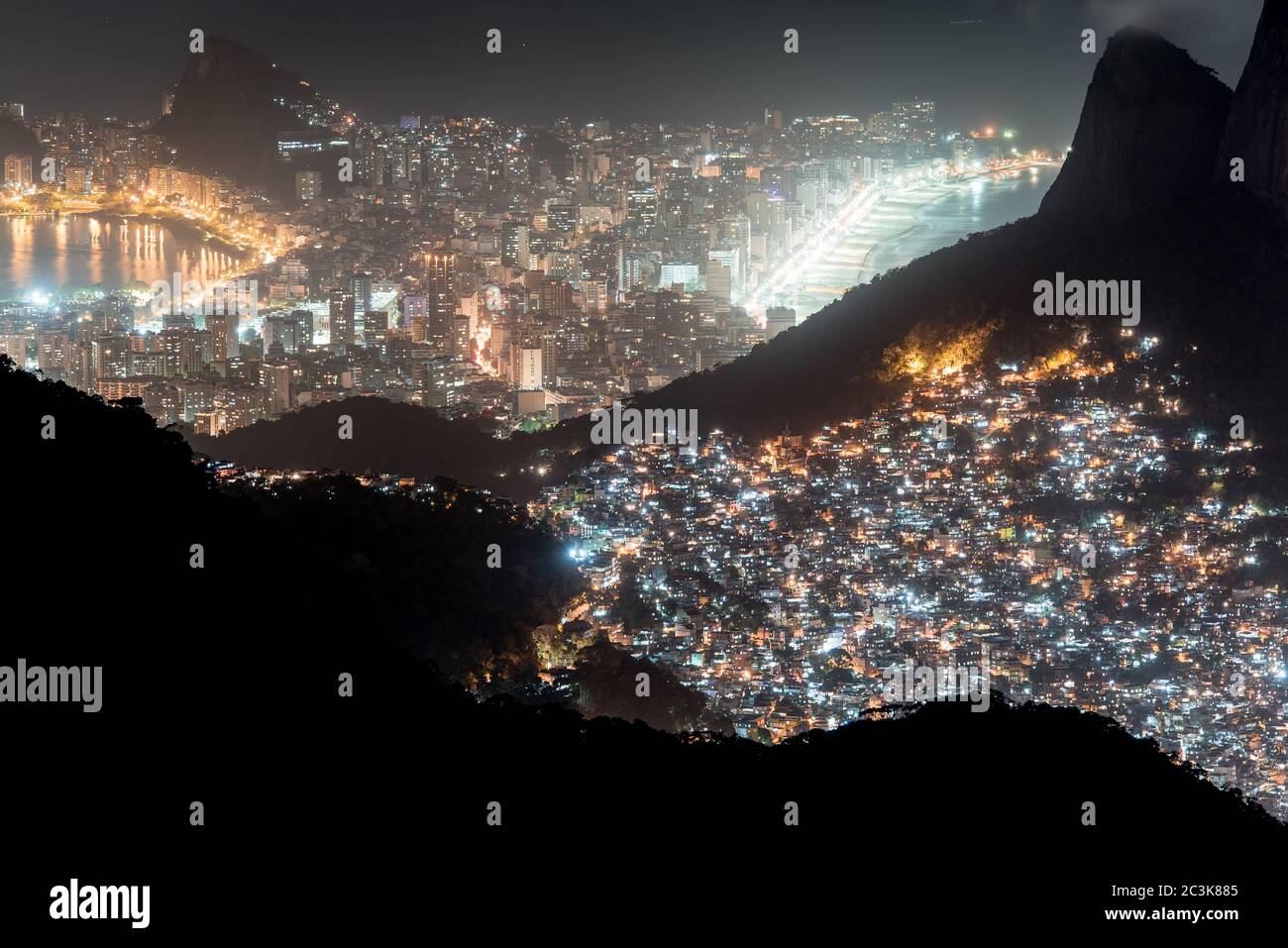 Vista notturna o Favela Rocinha nella montagna e quartiere Ipanema dietro a Rio de Janeiro, Brasile. Foto Stock