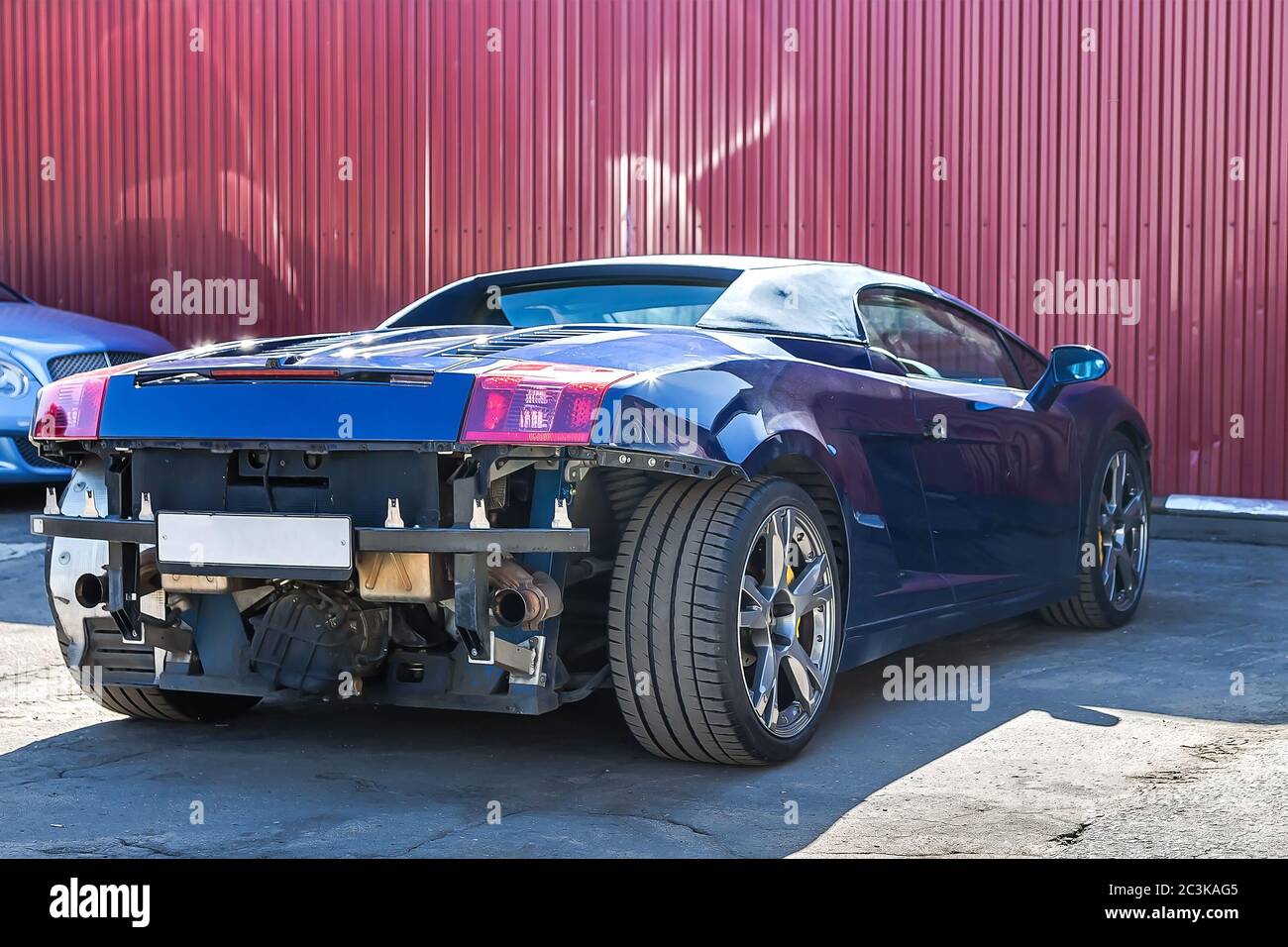 Cabriolet Super CAR. Danni al paraurti posteriore e anteriore dopo un incidente. Servizio e messa a punto. Sullo sfondo della parete di ferro Foto Stock