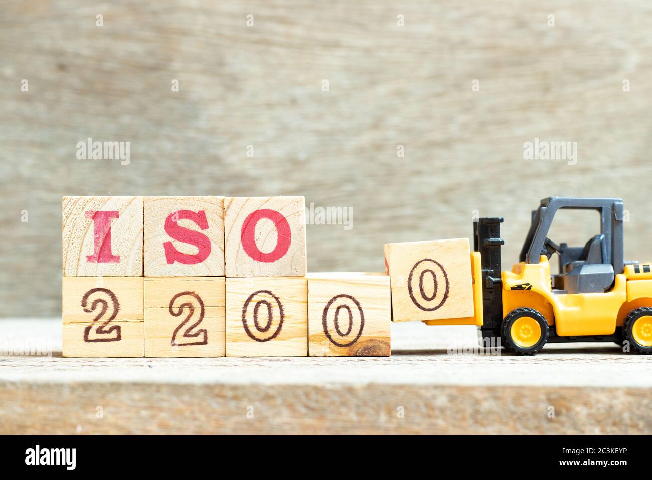Carrello giocattolo tenere il blocco di lettera 0 per completare la parola iso 22000 su sfondo di legno Foto Stock