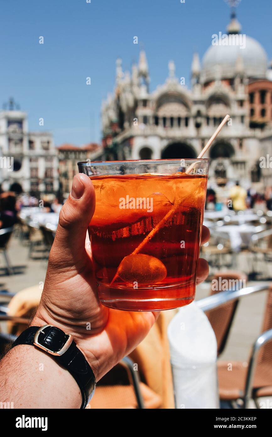 Primo piano verticale di una persona che tiene un bicchiere da cocktail mentre si siede nella caffetteria Foto Stock