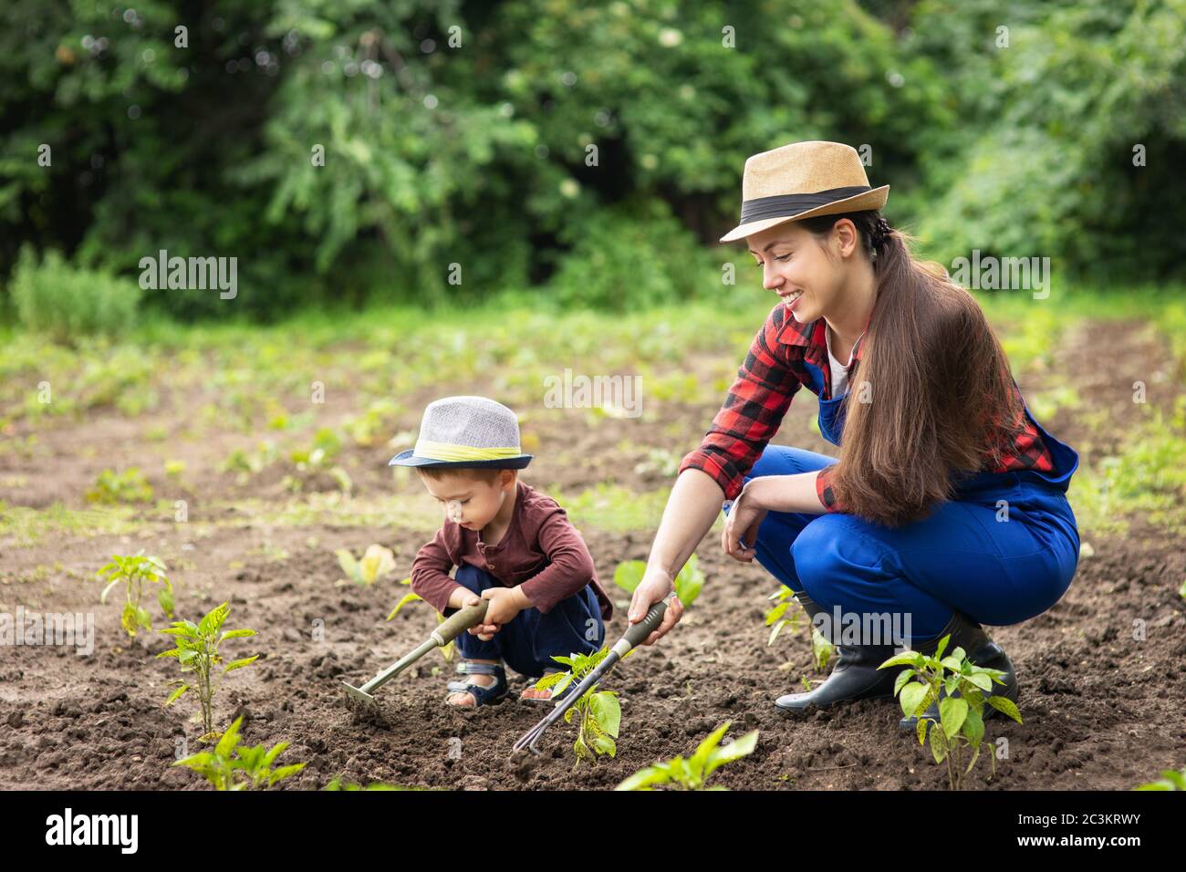 donna giardiniere e piccolo ragazzo giardino di erbaccia Foto Stock