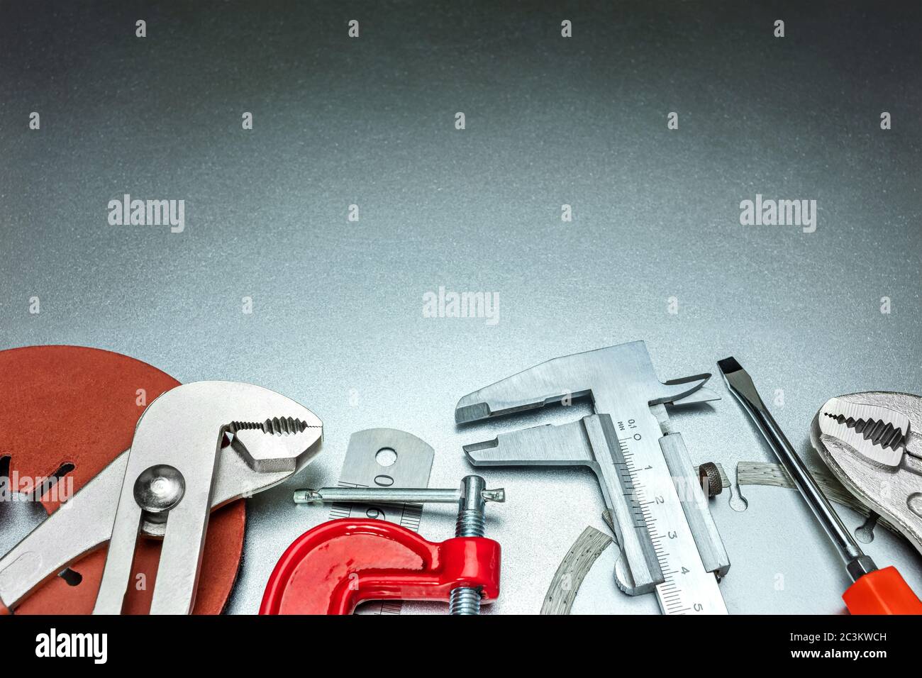 set di utensili manuali diversi su fondo metallico - chiave regolabile, pinze, morsetto, disco abrasivo Foto Stock