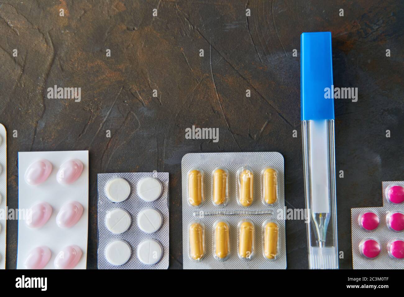 Pillole capsule medicina salute su sfondo scuro vista dall'alto, concetto di farmacia medica. Pillole diverse su sfondo scuro con spazio di copia. Foto Stock