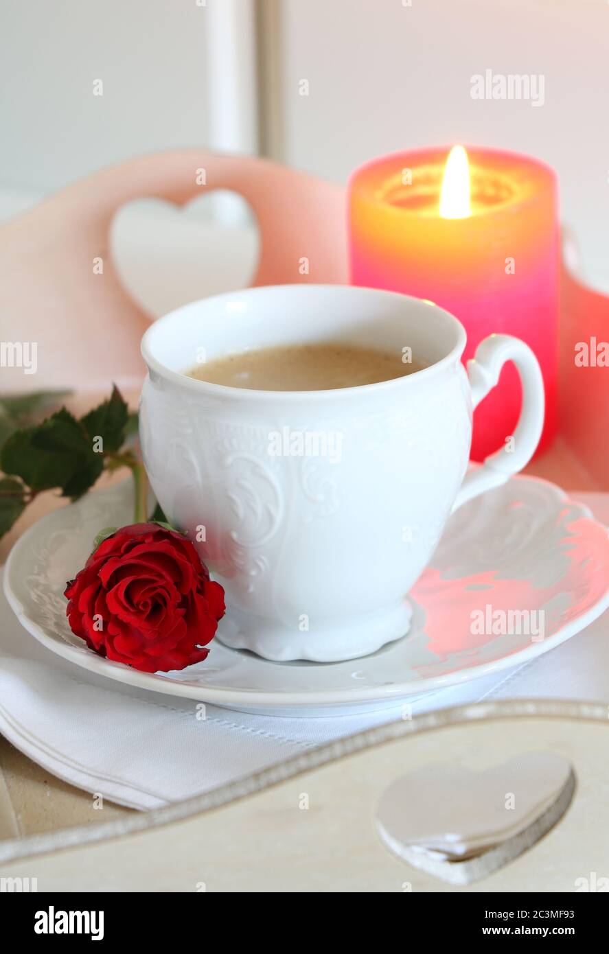 decorazione del tavolo in bianco con tazza di caffè, rosa e candela Foto Stock