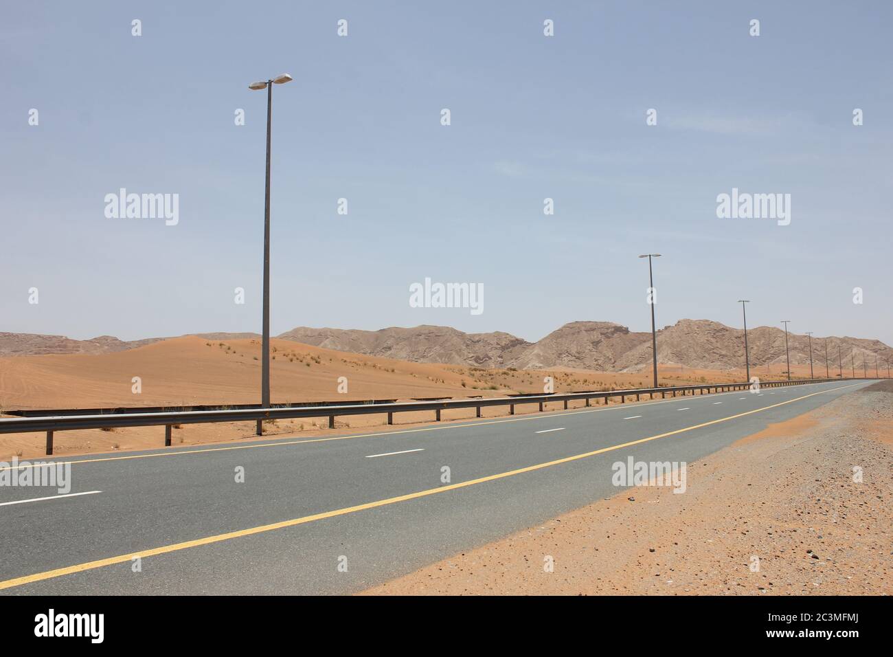 Una moderna autostrada asfaltata a due carrelli taglia le aride dune di sabbia del deserto. Foto Stock