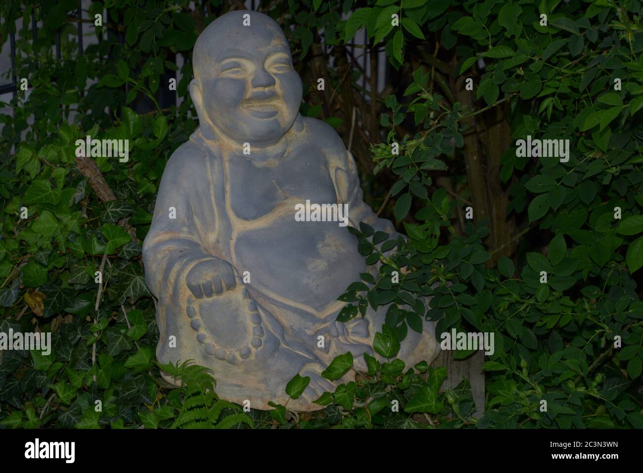 ridendo e sedendo buddha zen nel roseto Foto Stock