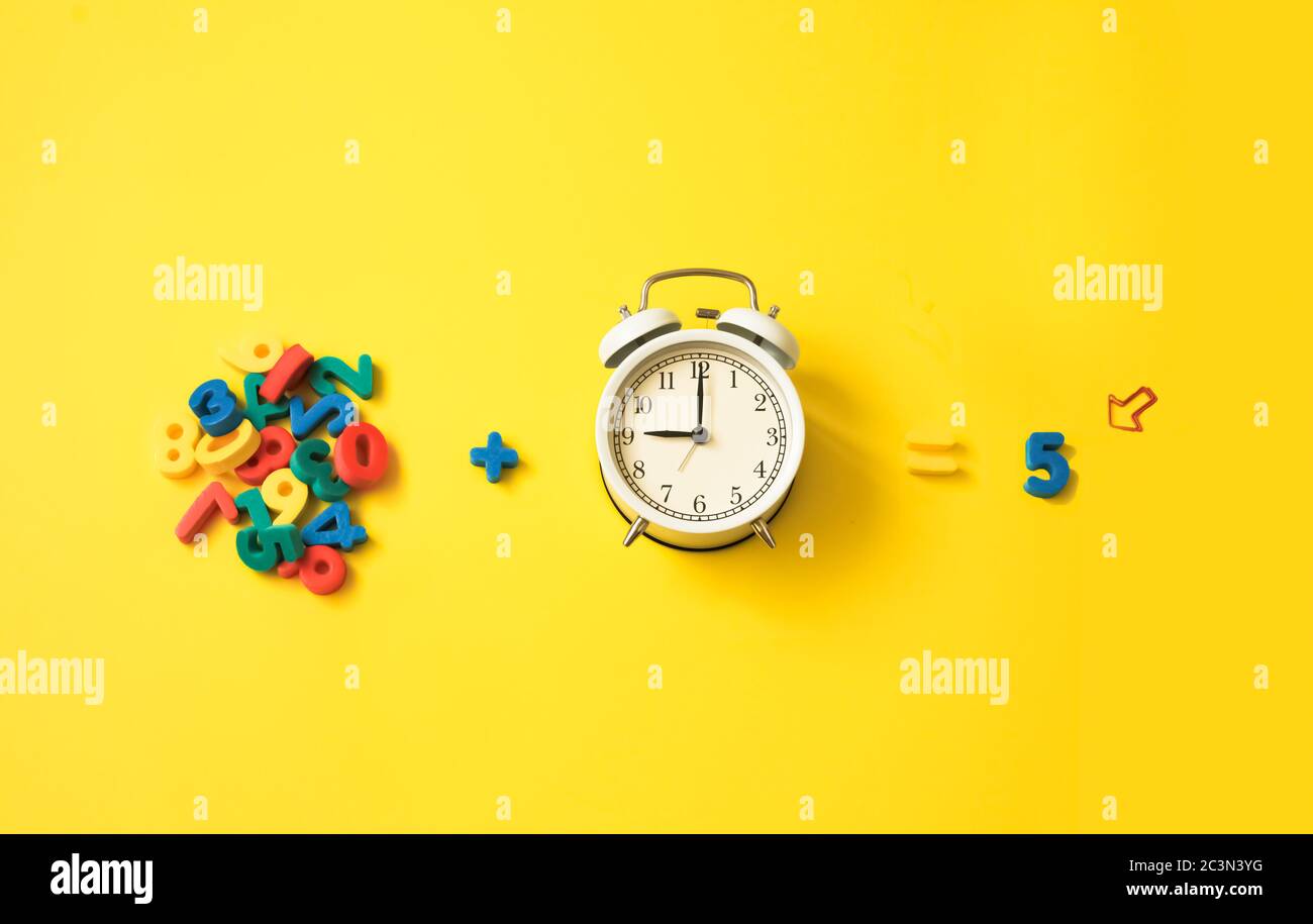 numeri e sveglia su sfondo giallo colorato. Insegnamento e istruzione, insegnamento della matematica dei bambini Foto Stock