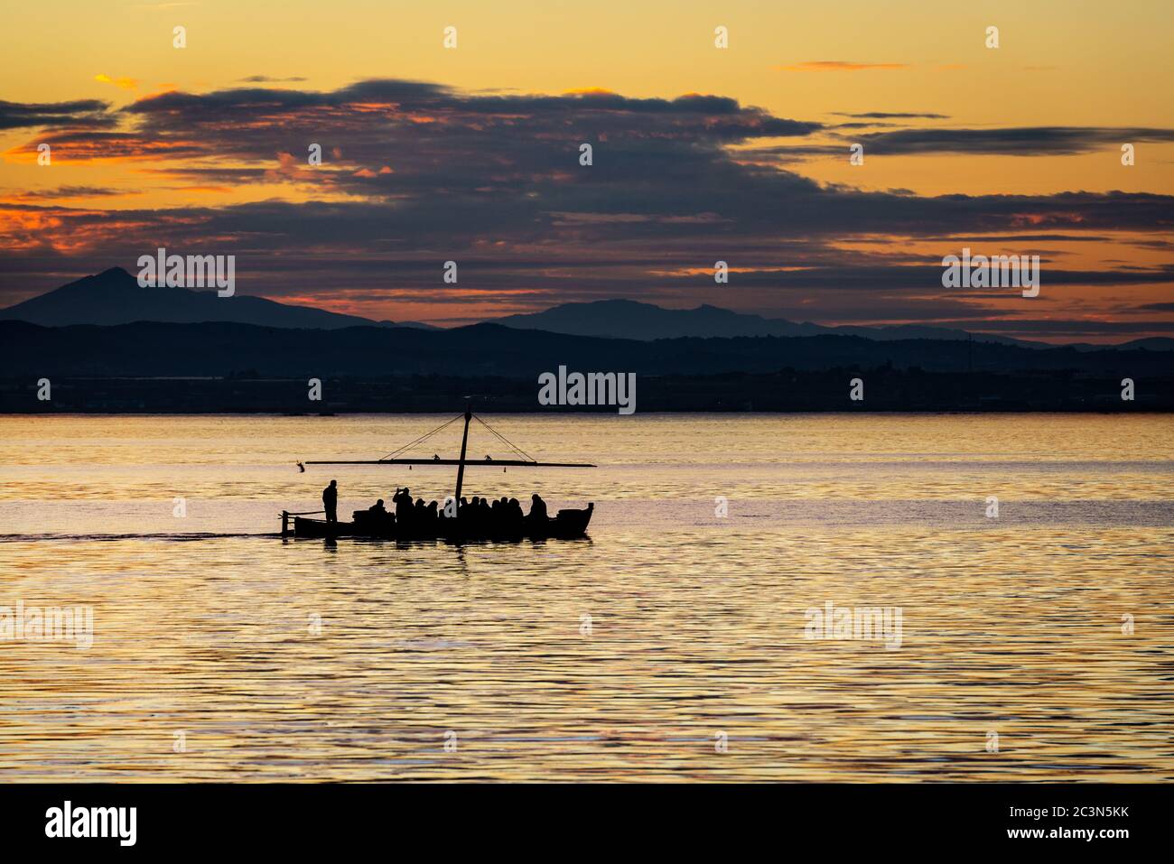 Silhouette di una piccola barca tradizionale al tramonto nell'Albufera a Valencia, una laguna d'acqua dolce e un estuario nella Spagna orientale. Foto Stock
