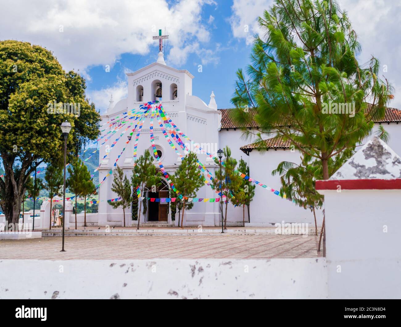 Vista impressionante della chiesa di San Lorenzo e del suo parvis con colorate bandiere di preghiera, Zinacantan, Chiapas, Messico Foto Stock