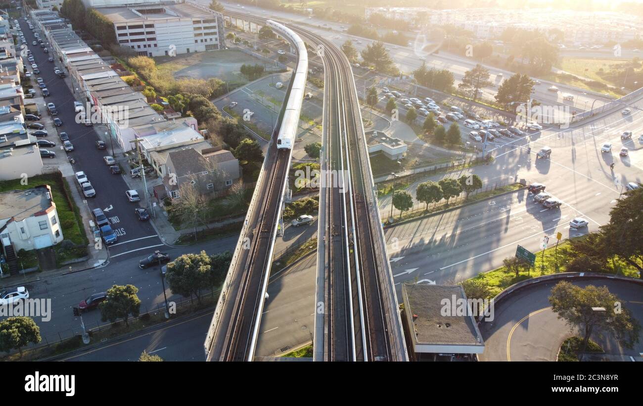 Scatto aereo del transito rapido della zona della baia di San Francisco il treno si avvicina alla stazione di Daly City, Foto Stock
