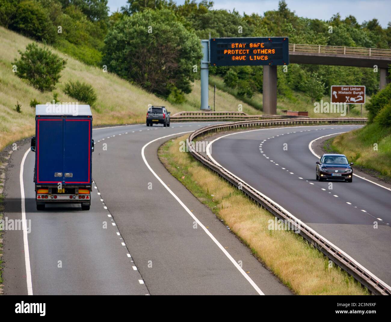 Traffico sulla A1 con il nuovo messaggio pandemico Covid-19 sul gantry 'Stay Safe Protect Others Save Lives', East Lothian, Scozia, Regno Unito Foto Stock