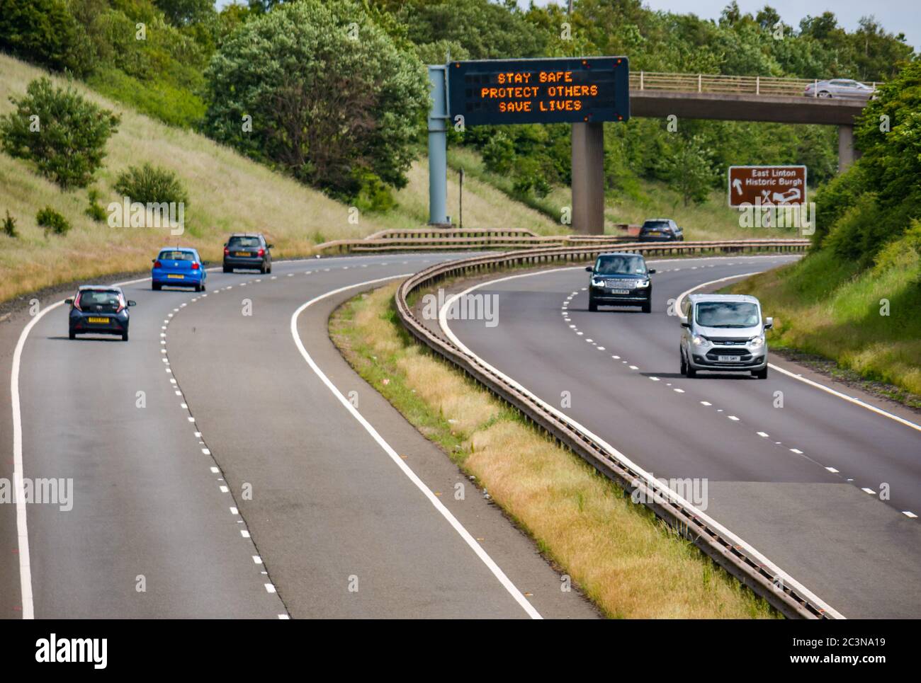 Traffico sulla A1 con il nuovo messaggio pandemico Covid-19 sul gantry 'Stay Safe Protect Others Save Lives', East Lothian, Scozia, Regno Unito Foto Stock