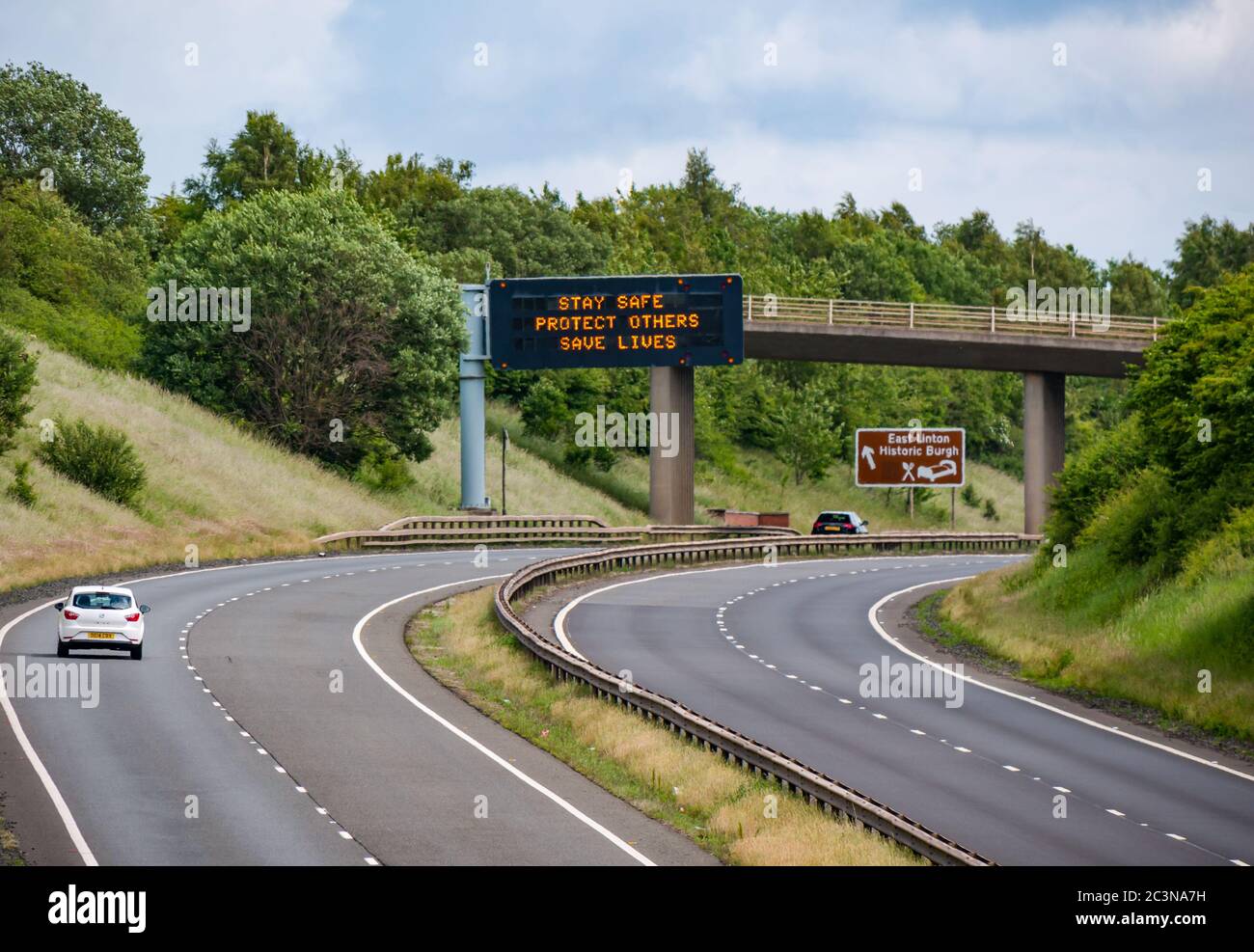Traffico sulla A1 con il nuovo messaggio pandemico Covid-19 sul gantry 'Stay Safe Protect Others Save Lives', East Lothian, Scozia, Regno Unito Foto Stock