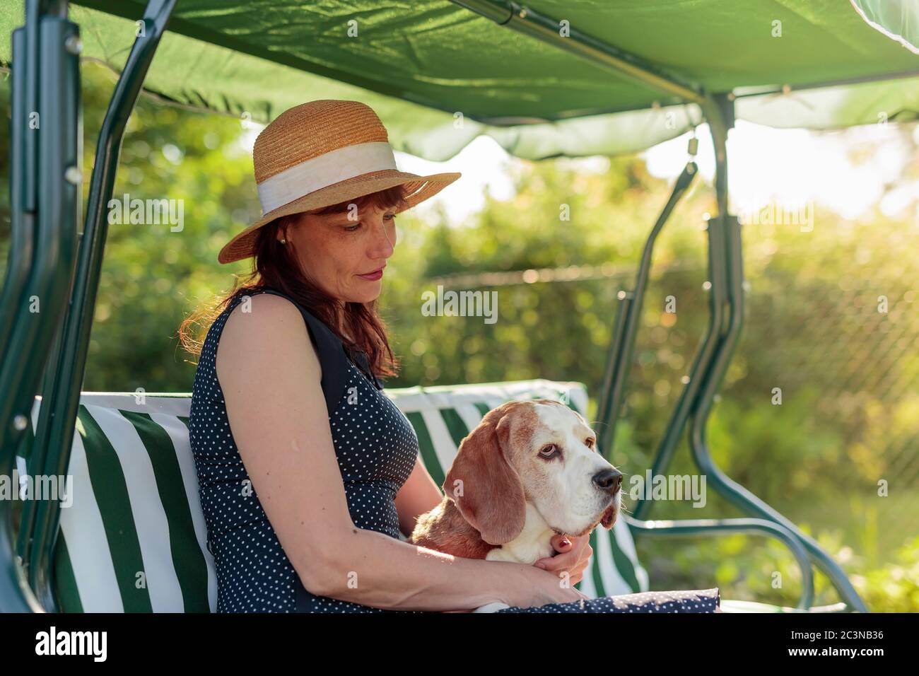 Ritratto di una donna matura con il cane su una panchina nel suo giardino. Foto Stock