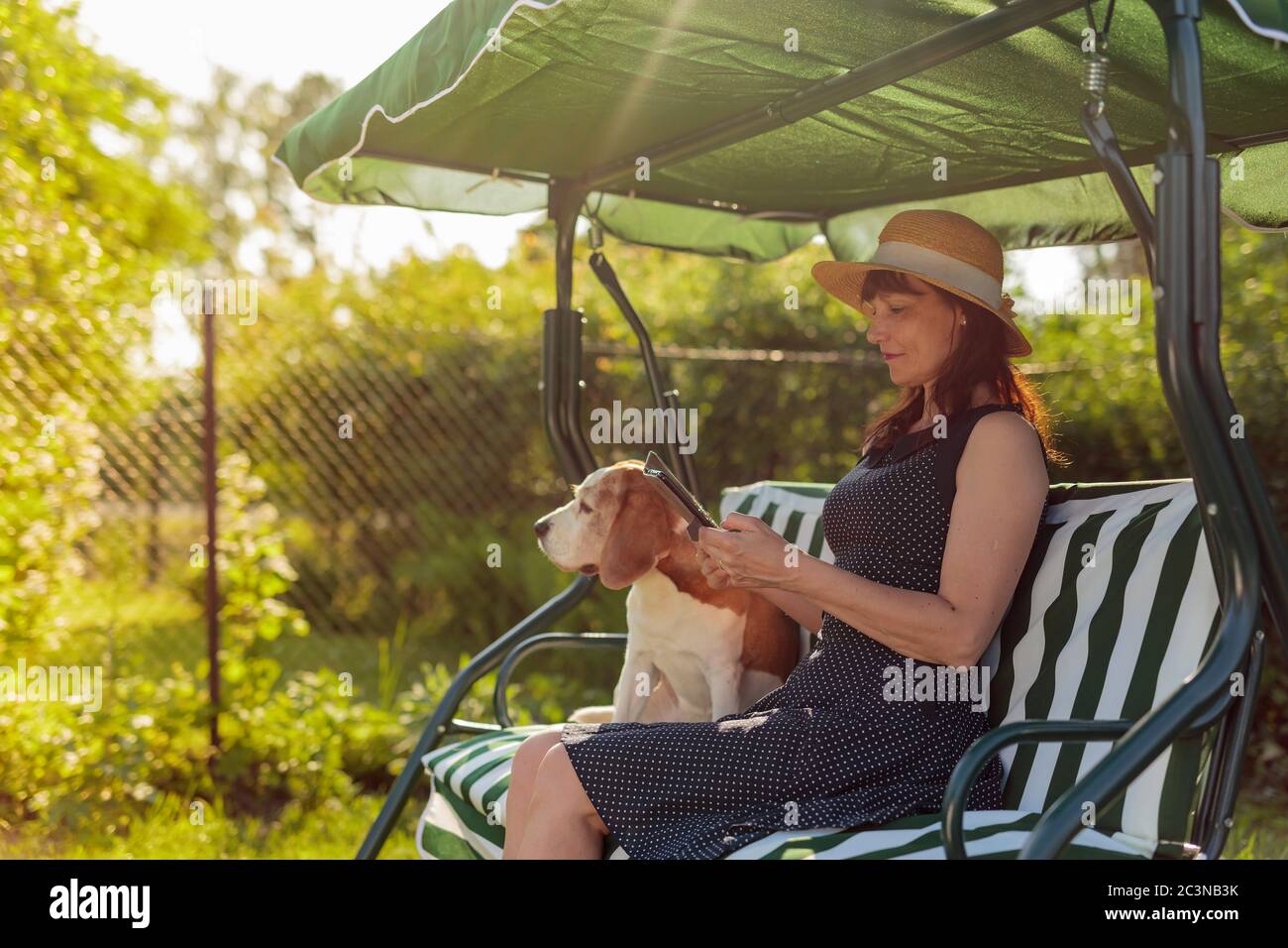 Ritratto di una donna matura con cane su una panchina in giardino. Foto Stock