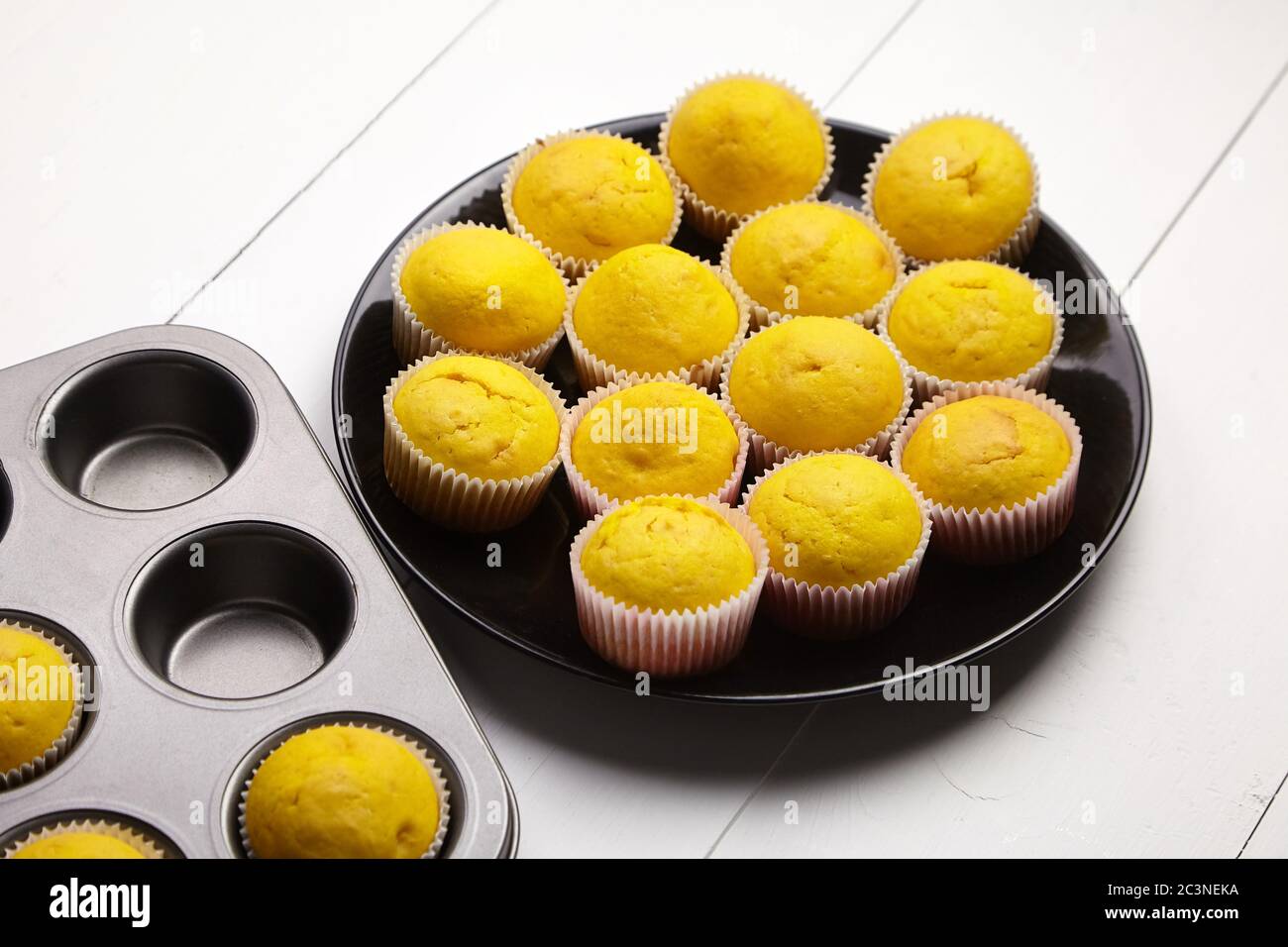 Cupcakes su piastra nera, vassoio da forno su tavolo di legno bianco. Muffin alla zucca. Panetteria fatta in casa Foto Stock
