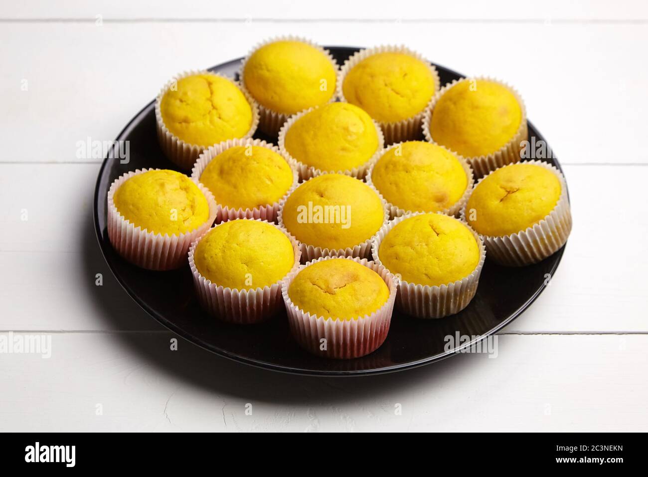 Cupcakes su piastra nera su tavolo di legno bianco. Muffin alla zucca. Panetteria fatta in casa, dolce dessert. Cibo a base di piante Foto Stock